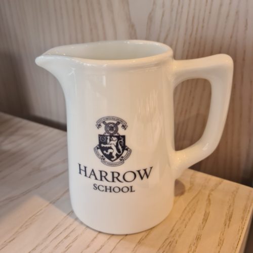 A white jug with the Harrow School crest on