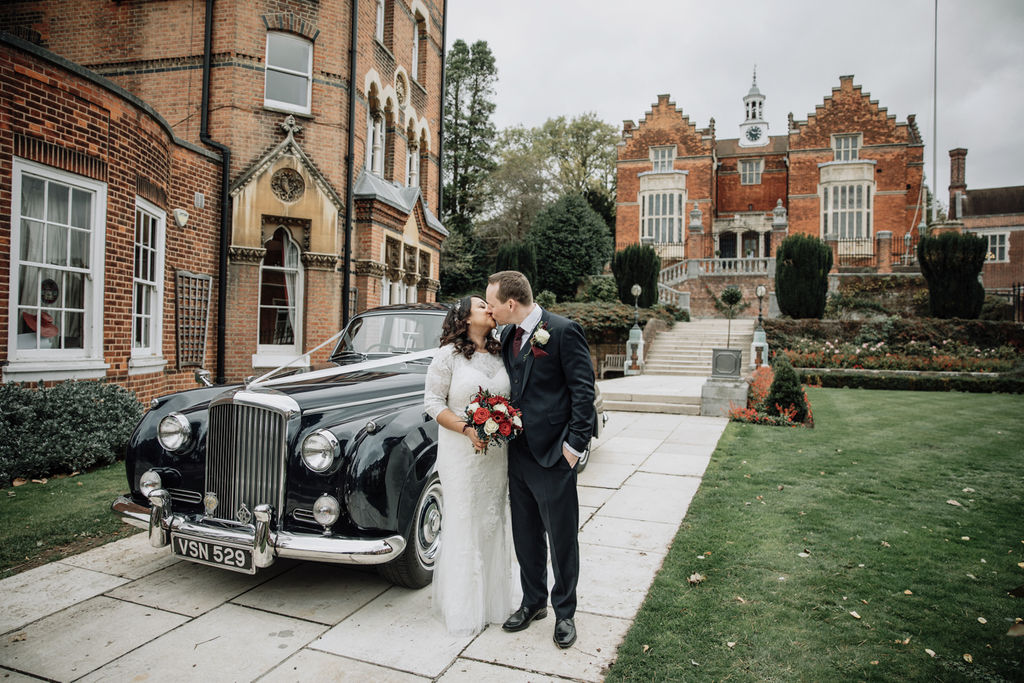 A couple in front of Harrow School with their wedding car